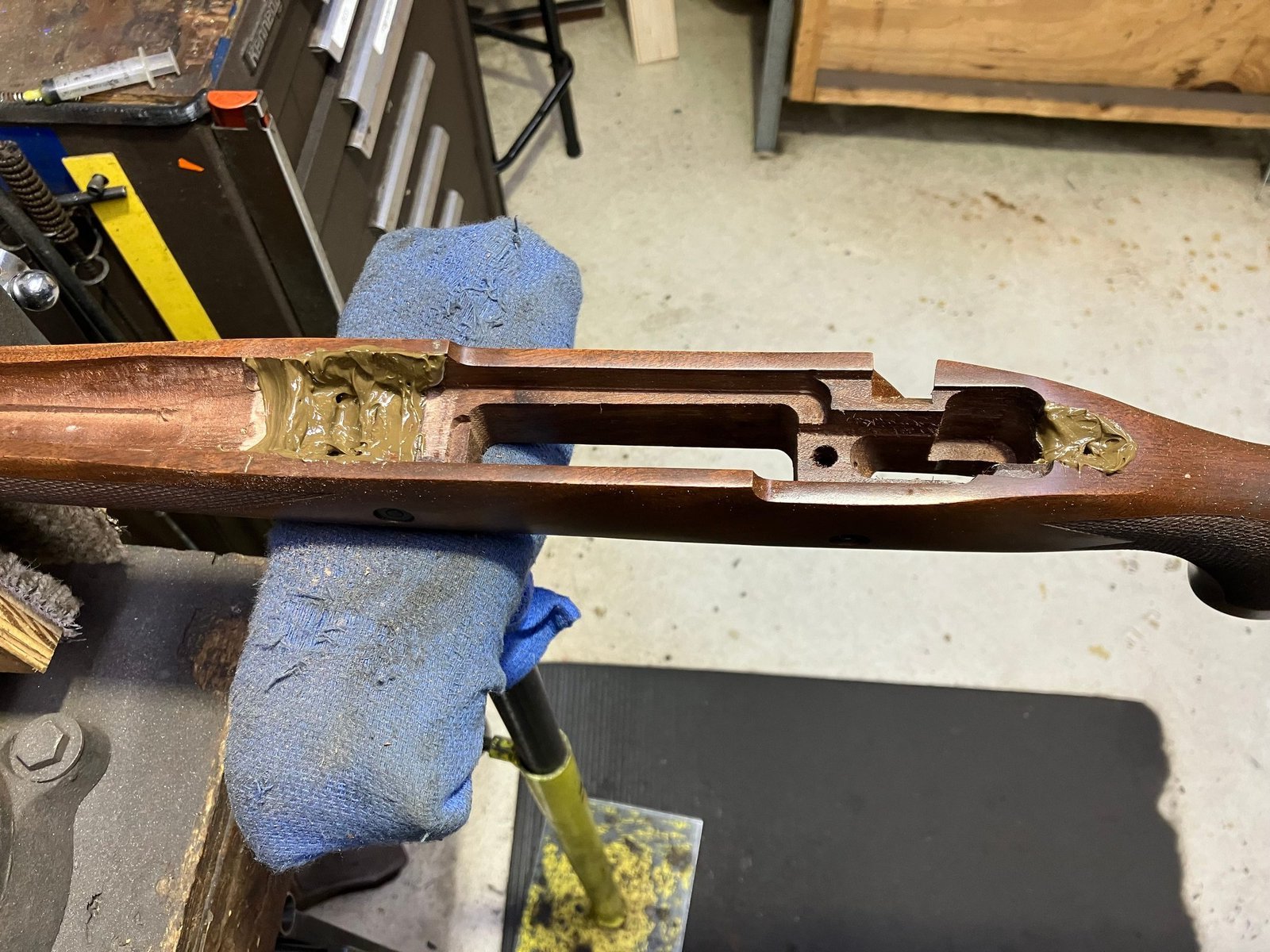 Wood rifle stock with glass bedding compound applied in the recoil lug inlet and near an action screw