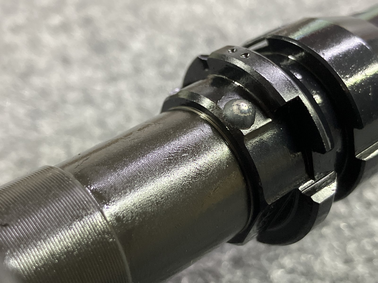 Close-up of a clean TIG weld bead on a pinned and welded muzzle device