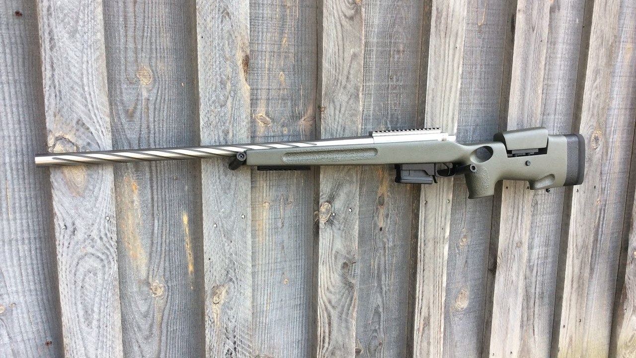 Custom bolt-action rifle in an olive green stock with a spiral-fluted stainless barrel