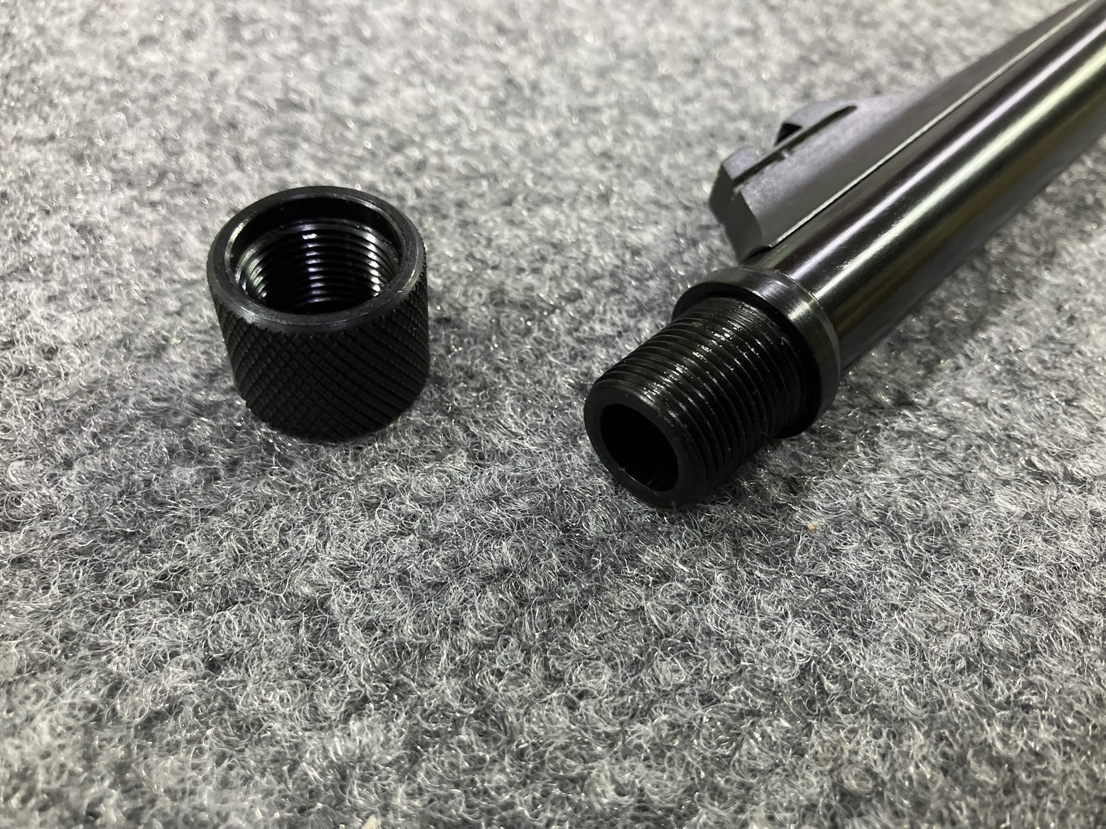 Muzzle end view of suppressor threads, blued threaded collar, and knurled thread protector