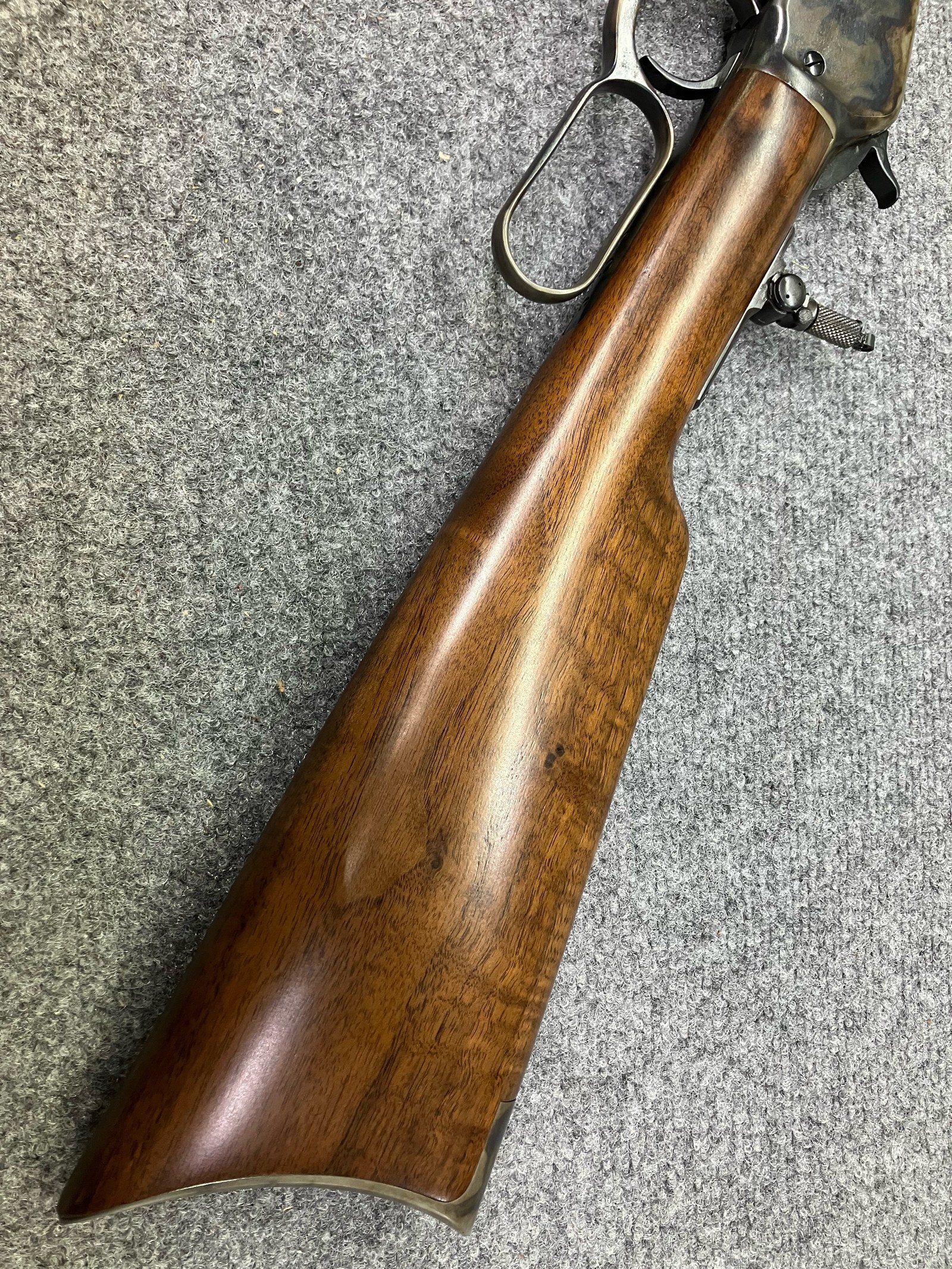 Satin finish on the pistol grip of a checkered walnut rifle stock