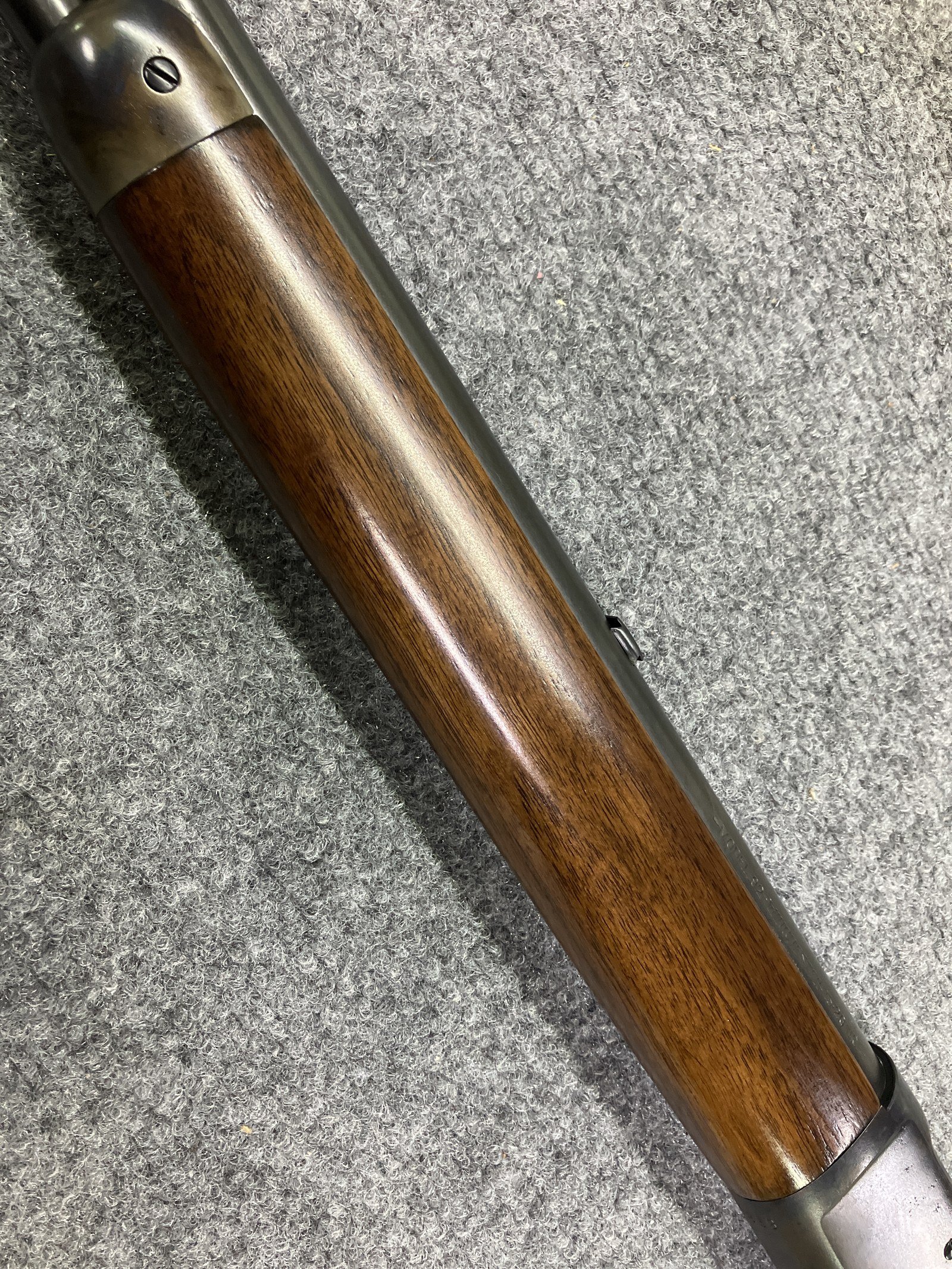 Satin finish on a checkered walnut forearm, with a blued barrel and front sight